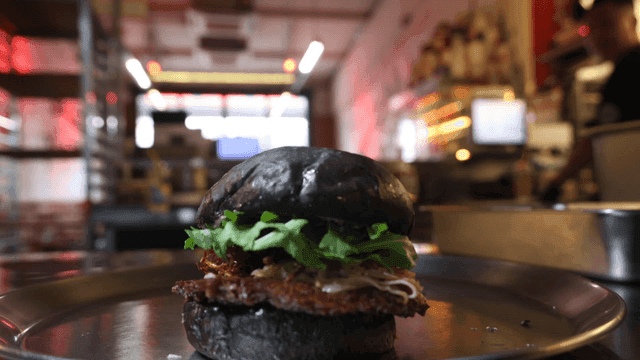 Black burger being prepared in a kitchen