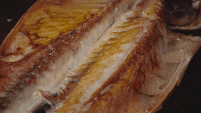 Grilled fish sizzling in a pan