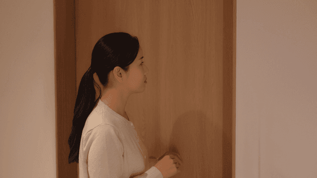 Middle-aged woman standing next to wooden door, kicked out