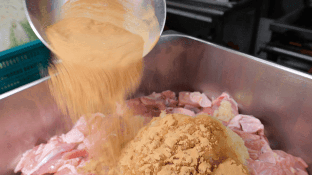 Seasoning chicken with spices in a kitchen