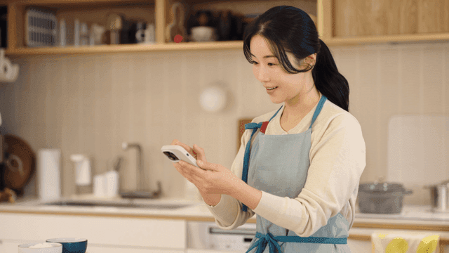 Woman in kitchen using smartphone