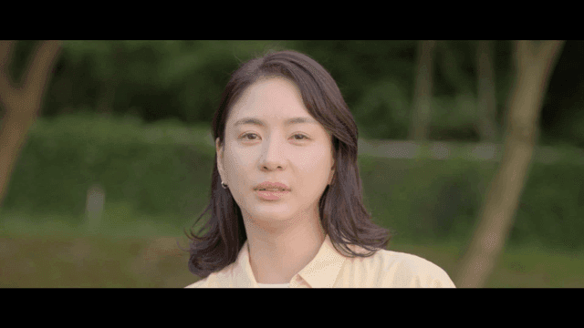 Woman in park looking straight ahead with faint smile