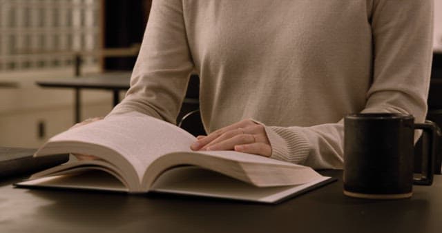 Person reading a book at a table with coffee