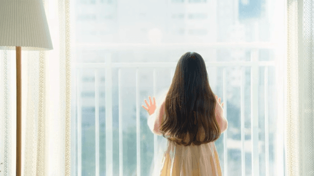 Child looking out the window in a bright living room