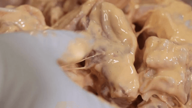 Chicken tossed in batter with gloved hands