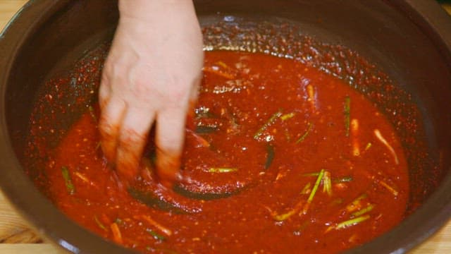 Preparing kimchi by adding bitter lettuce to spicy red pepper seasoning