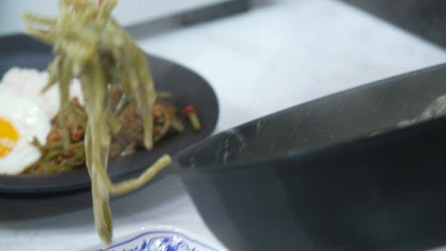 Stir-fried sweet potato stem in sesame oil, plated on a plate on the table