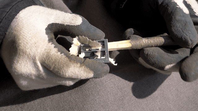 열필깎이 도구로 나무 막대를 다듬는 손