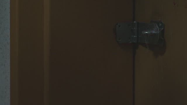 나무 문에 자물쇠를 걸어 잠그는 사람