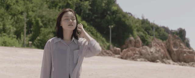 햇살이 비치는 해변에 서 있는 여성