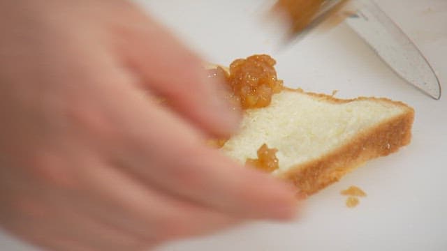 Spreading fruit jam on toast with a butter knife