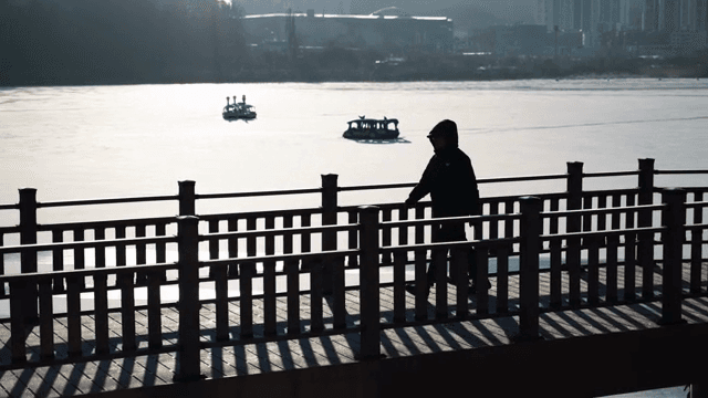 얼어붙은 호수 옆 다리를 걷는 사람