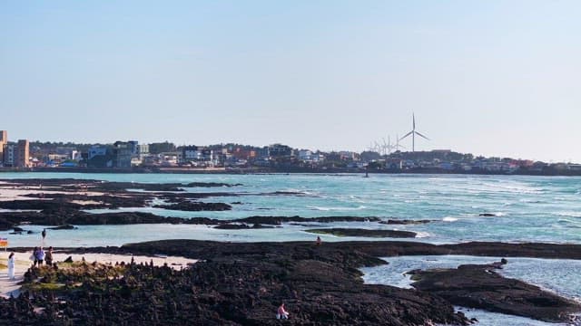 Coastal town with wind turbines and waves