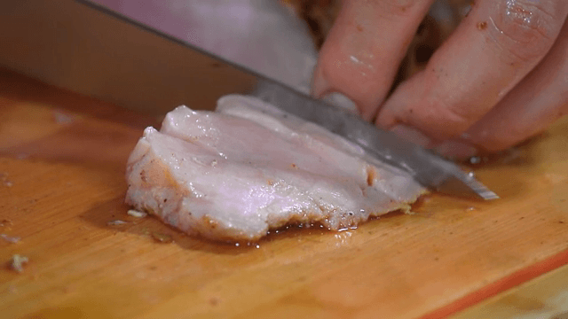 Slicing juicy pork on a wooden board