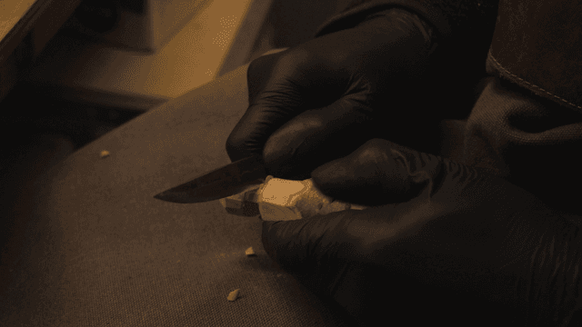 무릎 위에서 나무를 조각하는 사람