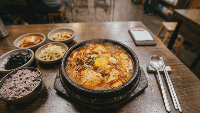 Soft tofu stew and side dishes on table