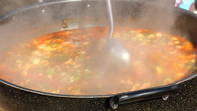 Stirring the hearty mustard leaf kimchi stew boiling in a pot with a ladle