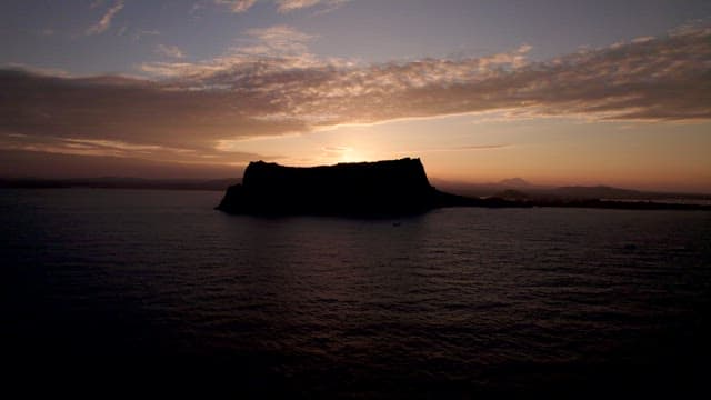 Silhouette of an Island under a Sky with a Rising Sun