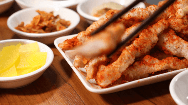 Chopsticks picking up fried meat seasoned with cumin and dipped in salt