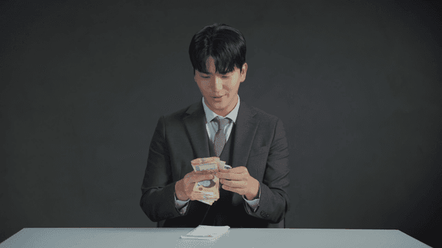 책상에서 돈을 세는 정장 입은 남자