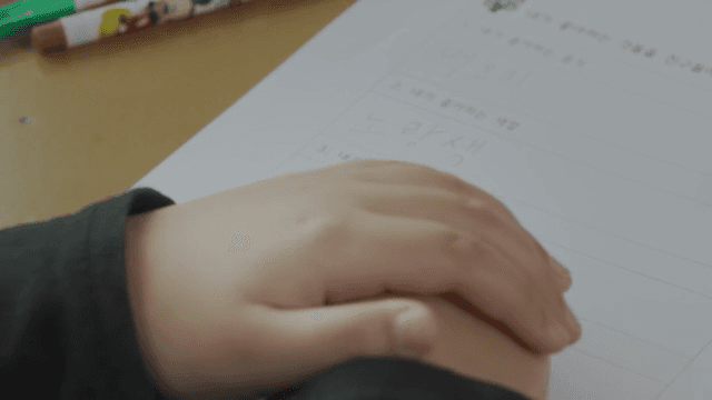 책상에 두 손을 올리는 아이