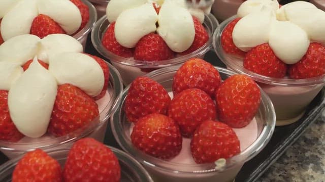 Strawberry desserts being decorated with whipped cream