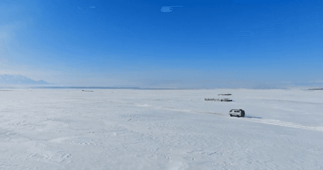 Vehicle traveling across a snowy plain