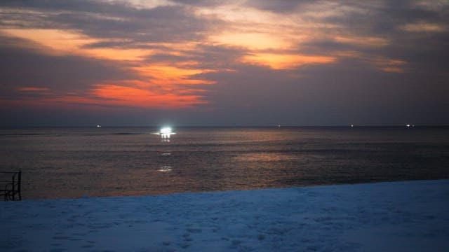 Boat on the sea during a vivid sunset with snowy shore