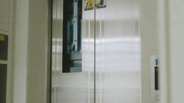 아파트 건물의 엘리베이터가 열리고 내리는 남자