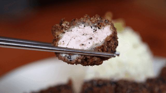 Crispy black pork cutlet picked up with chopsticks