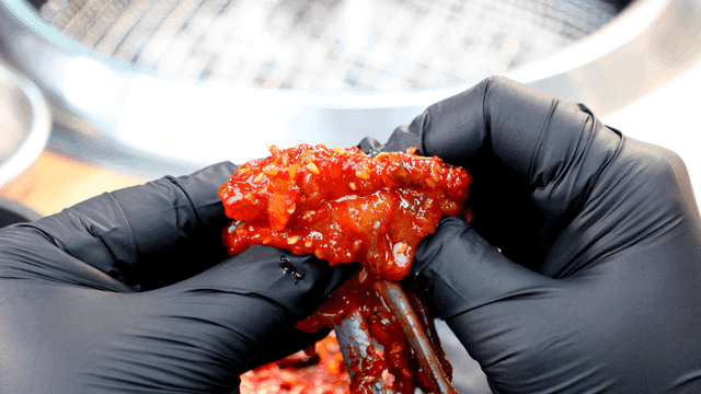 Spicy marinated crab squeezed out with gloved hands