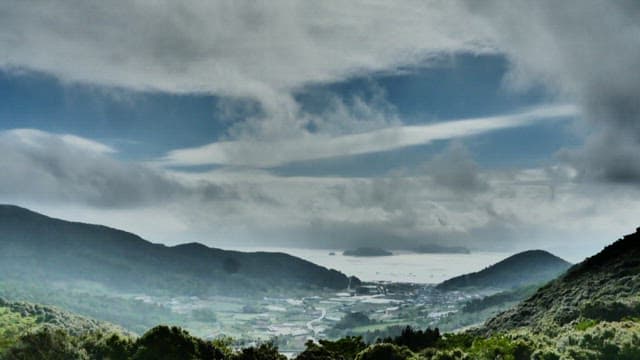 구름이 흘러가는 하늘 아래 산맥과 계곡