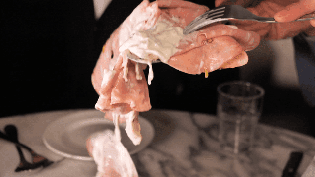 Person taking bite of mortadella pizza with cream sauce