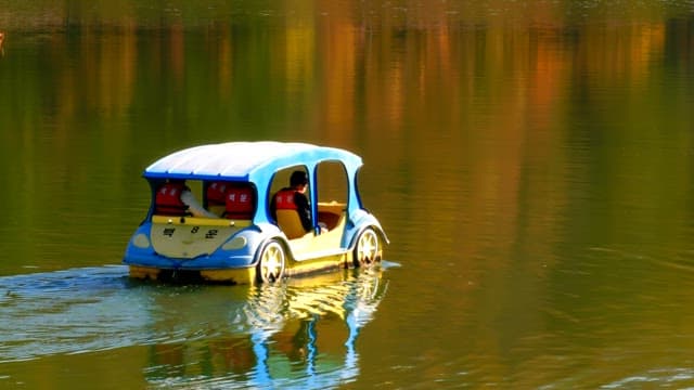 People riding a pedal boat on a serene lake