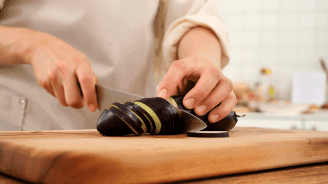 Slicing eggplant on a wooden cutting board