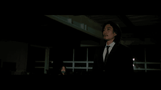 테이프로 입이 막힌 여성 앞에서 박수치는 정장을 입은 남성