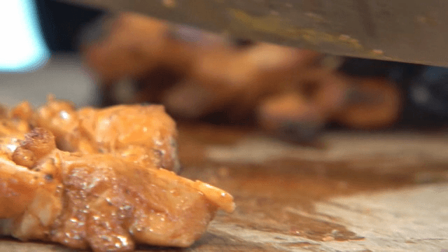 Slicing spicy stir-fried chicken on a cutting board