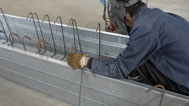 Worker welding metal beams in a factory