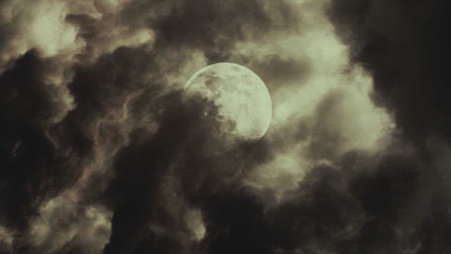 Full moon through dark and swirling clouds