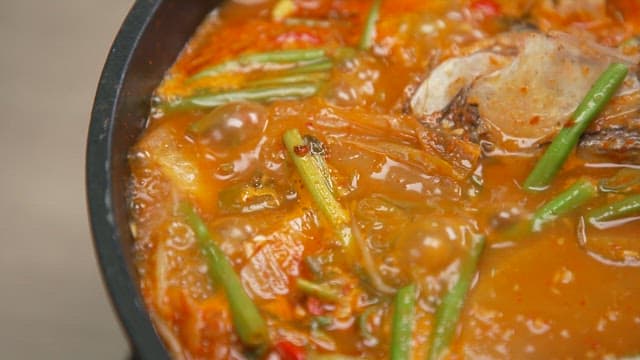 Spicy stew with fresh vegetables and fish is boiling