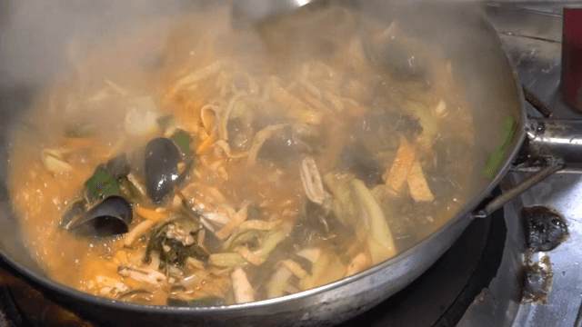 Spicy Seafood Noodle Soup with Napa Cabbage boiling in a pot