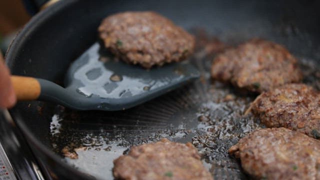 Grilling tteokgalbi with a spatula in a hot frying pan