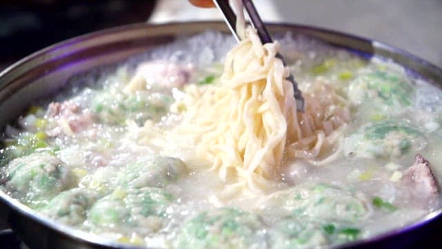Noodles being lifted from a boiling pot