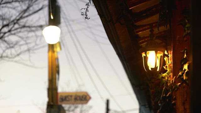 Evening street lamps lighting up near a guest house sign