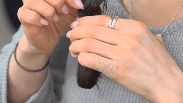 머리 끈을 이용해 꼼꼼하게 머리를 묶는 여성