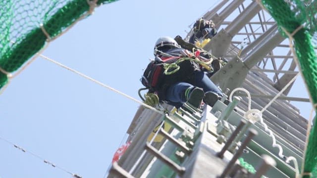 Workers climbing on a high transmission tower for maintenance work