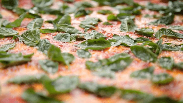 바질이 올라간 피자 위에 뿌리는 파마산 치즈