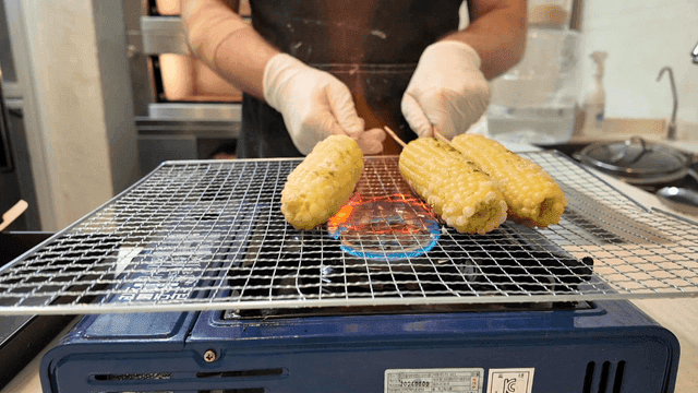 Cooking corn over gas burner in kitchen by chef