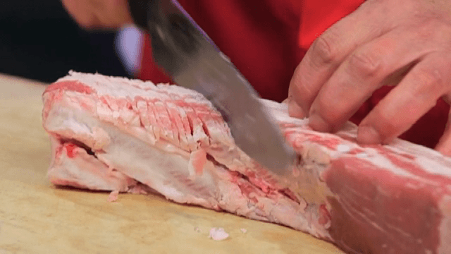 Scoring the raw pork belly with a knife
