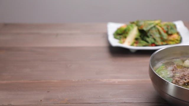 테이블 위 겉절이와 밥, 그리고 파가 들어간 맑은 육개장